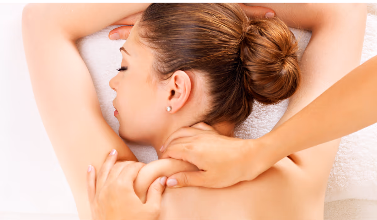 A therapist working the side of a client's neck and shoulder with both hands, the target area for work from home neck pain massage